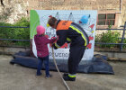 Feuerwehrmann und Kind mit Schlauch vor Plakatschild