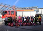 Gruppenfoto vor Feuerwehrauto, erste Reihe mit Schulranzen und Rucksackcover