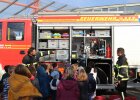 Feuerwehrleute zeigen Kinder etwas am Feuerwehrauto