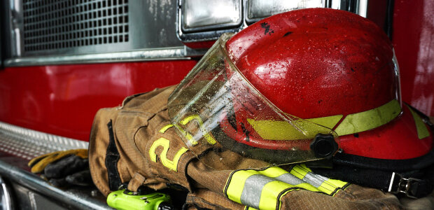 Nahaufnahme: Helm auf Feuerwehrkleidung vor Feuerwehrauto