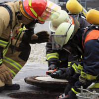 Drei Feuerwehrmänner schauen Richtung Boden